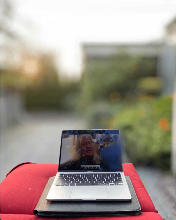 A laptop on a red cushion displays a paused video with a blurred outdoor background.