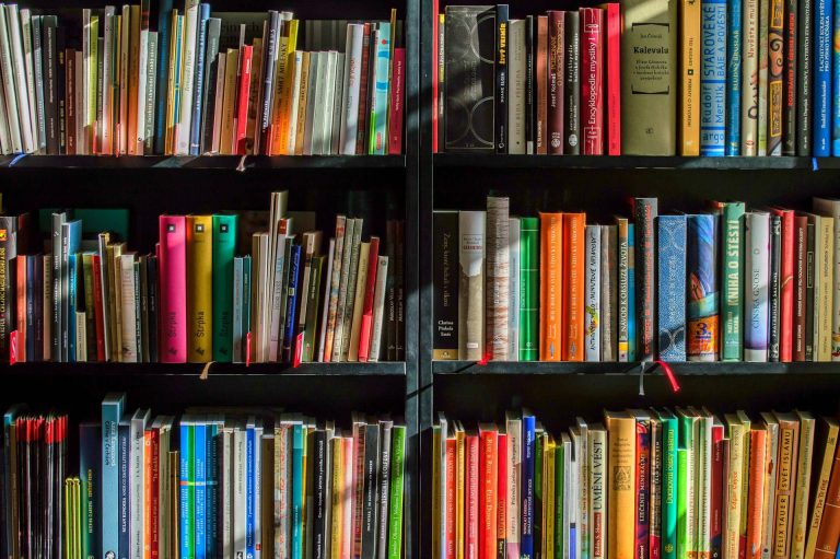 A bookshelf filled with a variety of colorful books and binders, arranged in multiple rows.