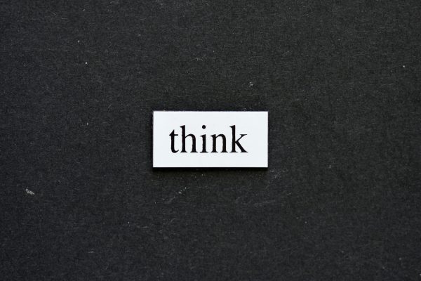 A white rectangular card with the word "think" written in black lowercase letters is placed on a dark gray background.